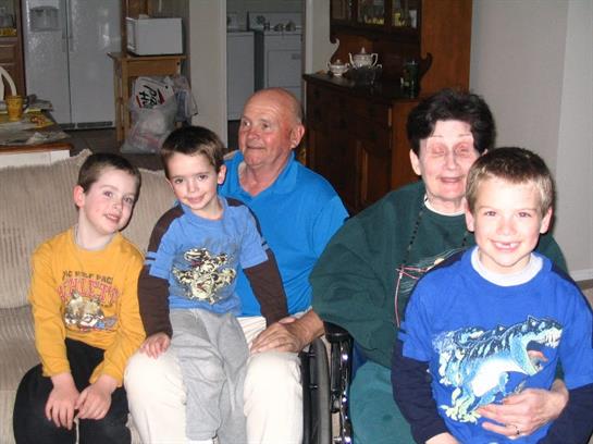 Grandparents sit with their three grandsons at home, sharing smiles and laughter in winter.