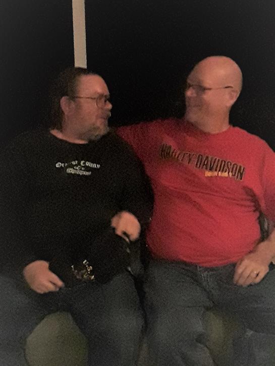 Two men share a laugh and a friendly moment in a casual setting.