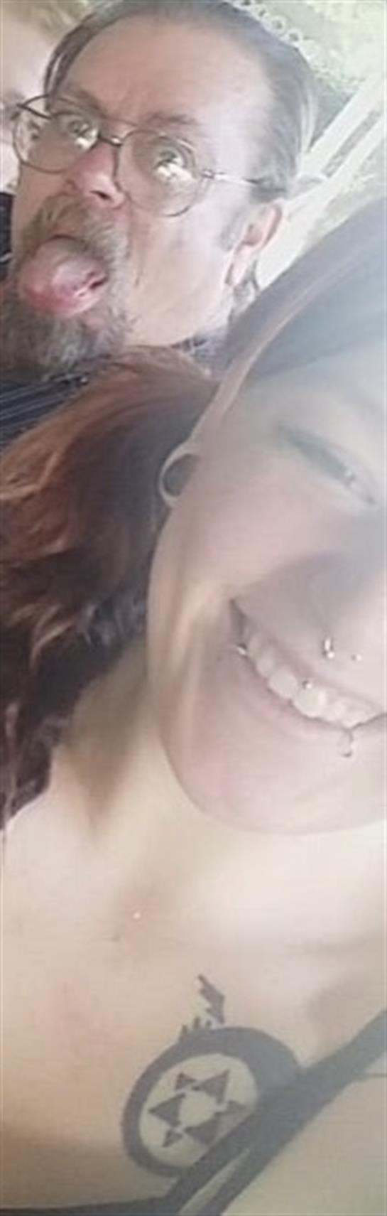 A cheerful person with piercings laughs and enjoys a lively gathering with friends.