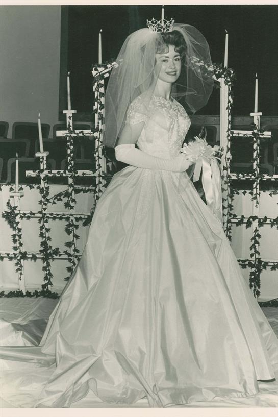 Bride in a white wedding dress poses in a church adorned with floral decorations and candles.