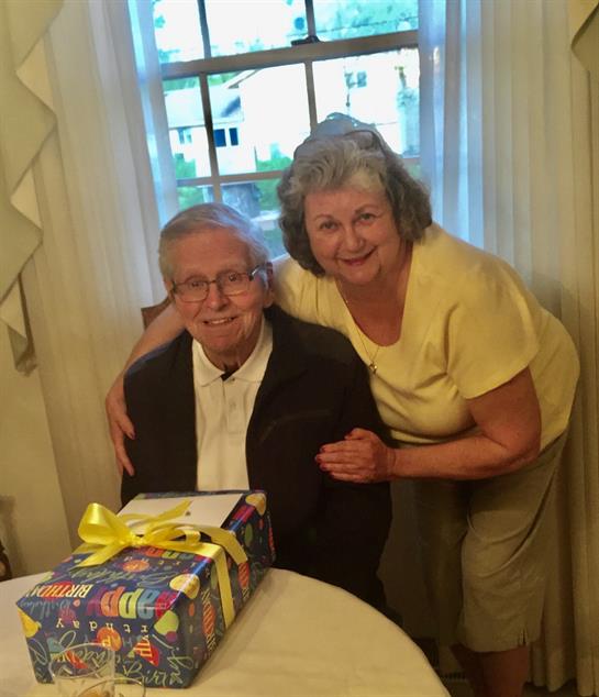 Family members are smiling and celebrating a special moment together with a gift present.