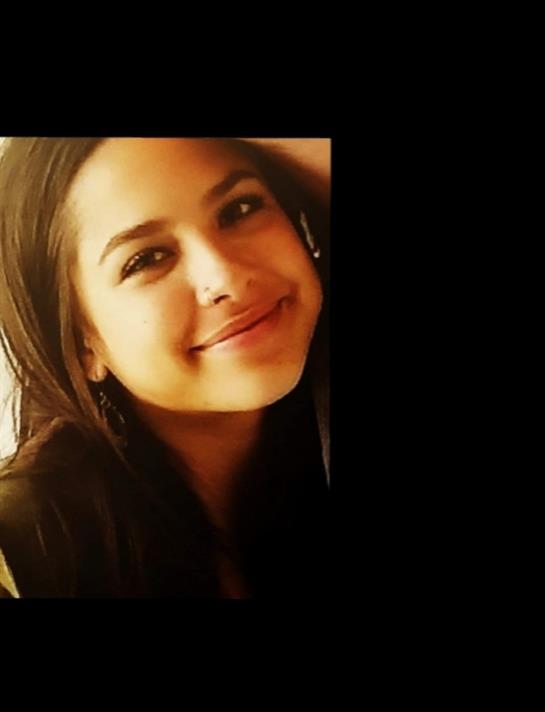 Young woman with long hair smiles at the camera, radiating joy and warmth.