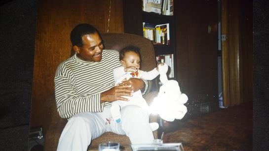 Father enjoys playful moments with his baby while sitting in a comfortable chair indoors.