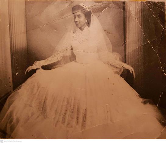 A woman elegantly poses in a beautiful vintage lace wedding gown with a long veil.