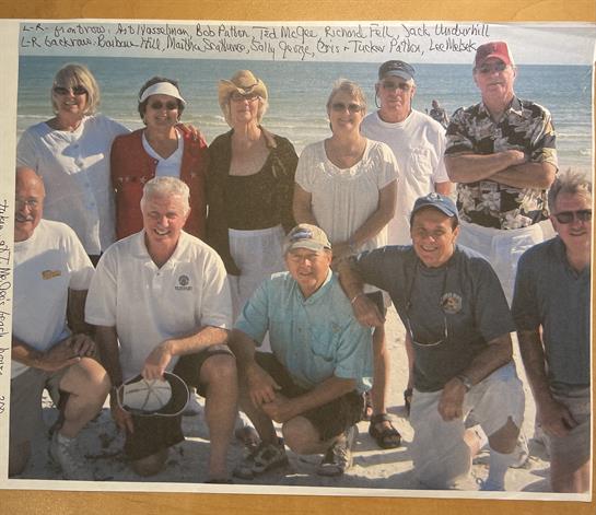 A cheerful group gathers on the sand, celebrating friendship and enjoying the beach atmosphere.