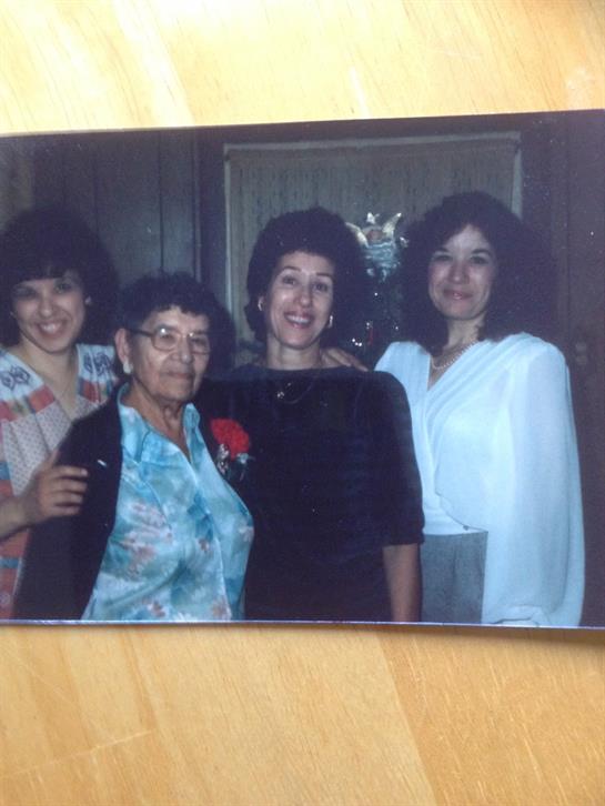 Four women of different generations smile together in a cozy interior during a family gathering.