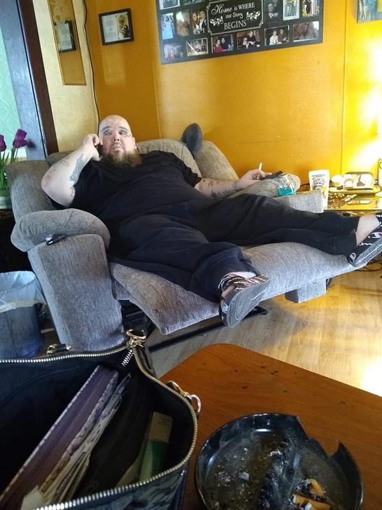 A man sits comfortably on a couch, chatting on the phone in a warm, inviting living space.