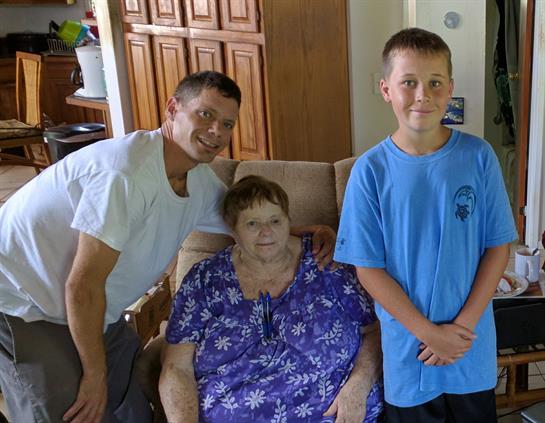 Three family members share smiles while sitting in a comfortable living room setting.