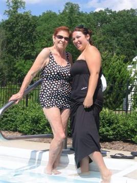 Women smile while posing near the pool, showcasing swimsuits and enjoying the warm weather.