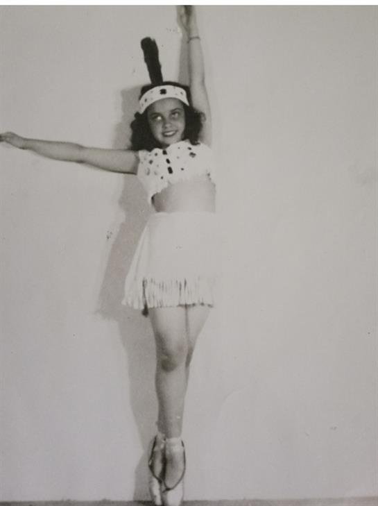 A joyful young dancer showcases a spirited pose in a playful costume, exuding enthusiasm and energy.