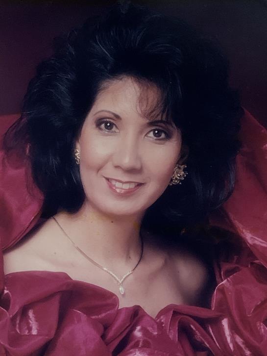 A woman is showcasing elegance in a vibrant red gown, smiling warmly with delicate accessories.