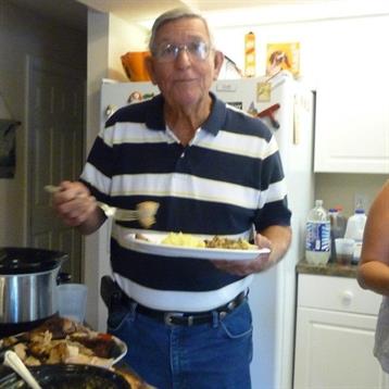 An elderly man enjoys serving food at a family gathering in a cozy home kitchen.
