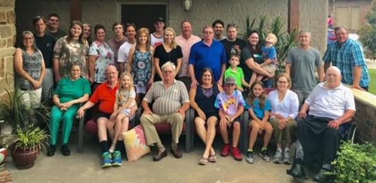 Large family poses together outdoors, smiling and enjoying time together in a warm atmosphere.