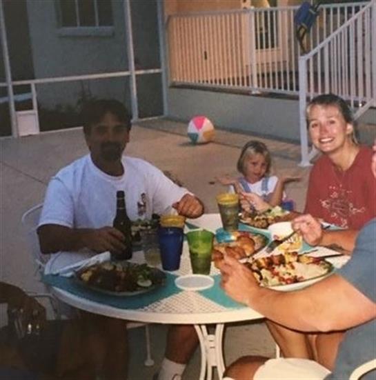 Four people share a joyful meal at a table on a warm summer evening by the poolside.