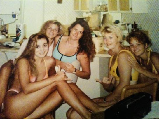 Friends relax in a bright kitchen, sharing smiles and summer vibes over refreshing drinks.