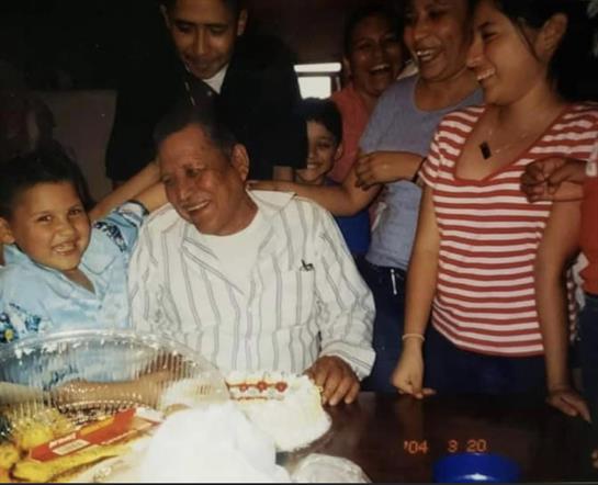 A loving family surrounds an elder during a birthday celebration with cake, laughter, and joy.