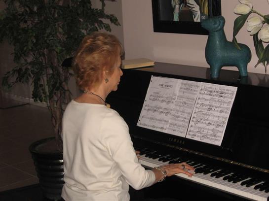 A woman is playing piano using sheet music in a warmly decorated living room.