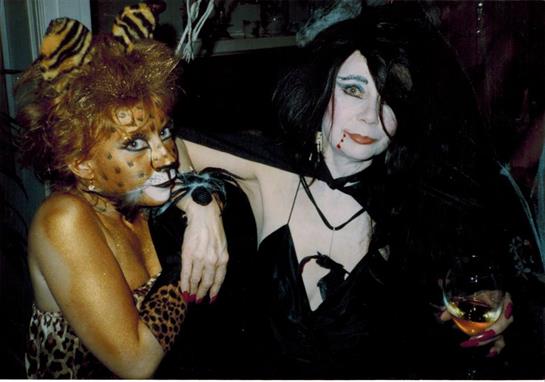 Costumed figures engage in lively interaction at an evening event, displaying elaborate outfits.