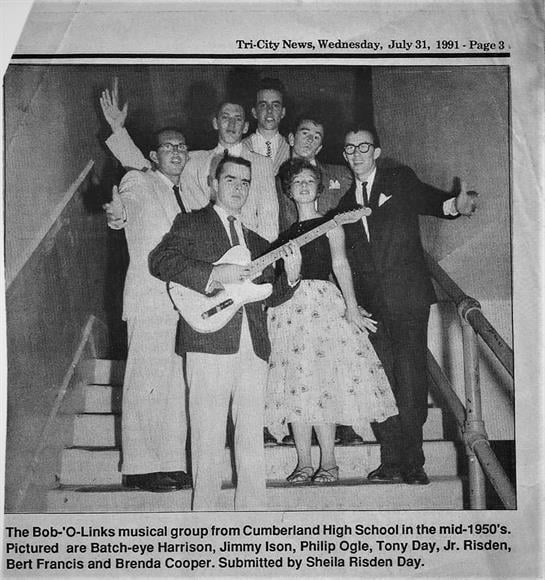 A lively musical group poses on stairs with instruments and cheerful expressions, showcasing talent.