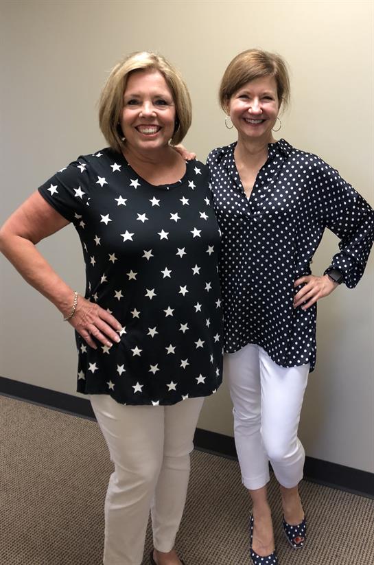 Two women stand side by side, showcasing their unique fashion styles with cheerful smiles.
