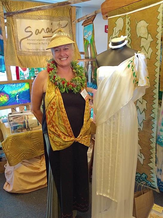 Artisan stands proudly beside a unique garment at a lively craft event, showcasing local talent.