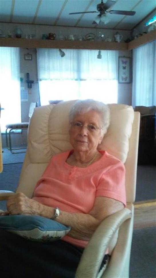 Elderly woman relaxes in a chair, surrounded by a warm and inviting room with natural light.