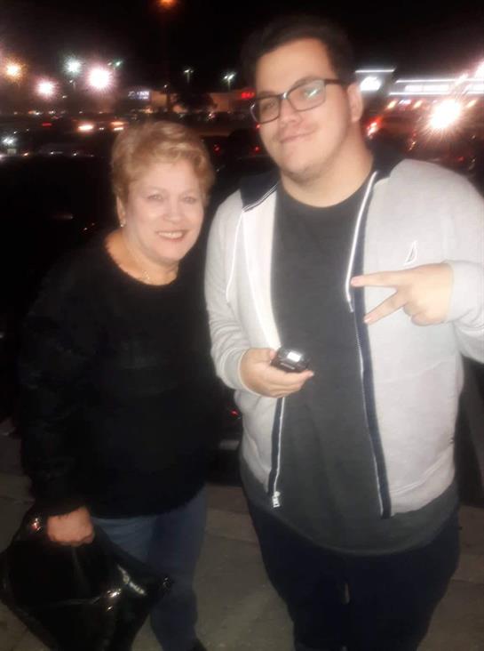 Two individuals are standing together in an urban setting at night, smiling and having fun.