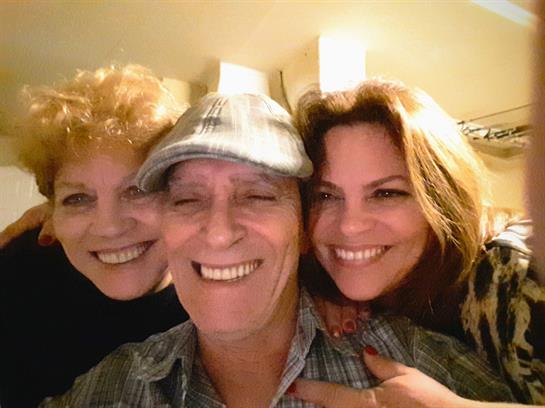 Three friends share smiles and laughter in a cozy atmosphere at a night gathering.