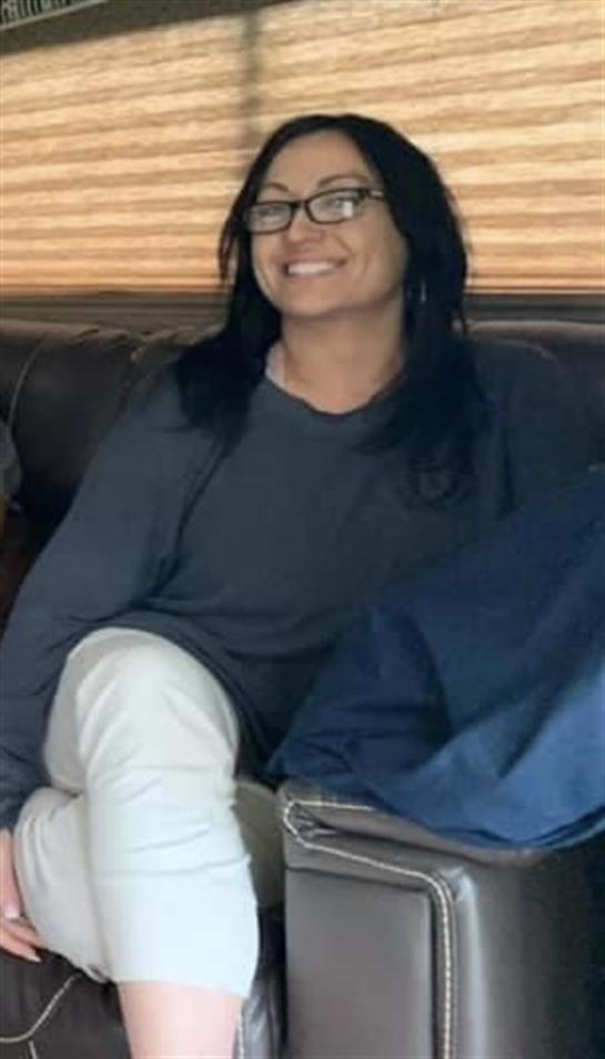 A person with long hair smiles on a couch, relaxing in the living room.