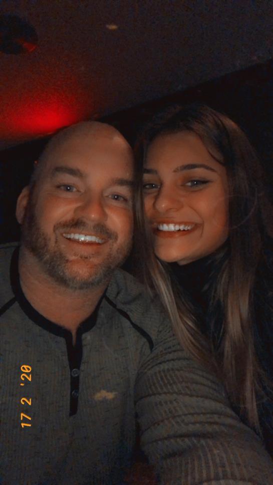 Two people enjoy each other's company while taking a selfie in a cozy, illuminated setting.