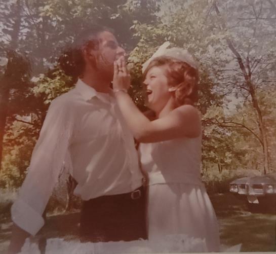 A man and a woman share a joyful, playful interaction in a lush green park on a sunny day.