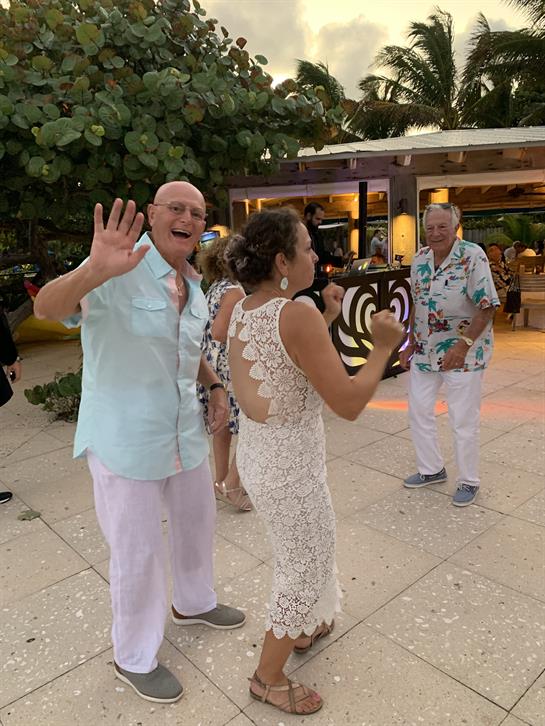 Guests celebrate together outdoors as they dance joyfully during a vibrant sunset gathering.