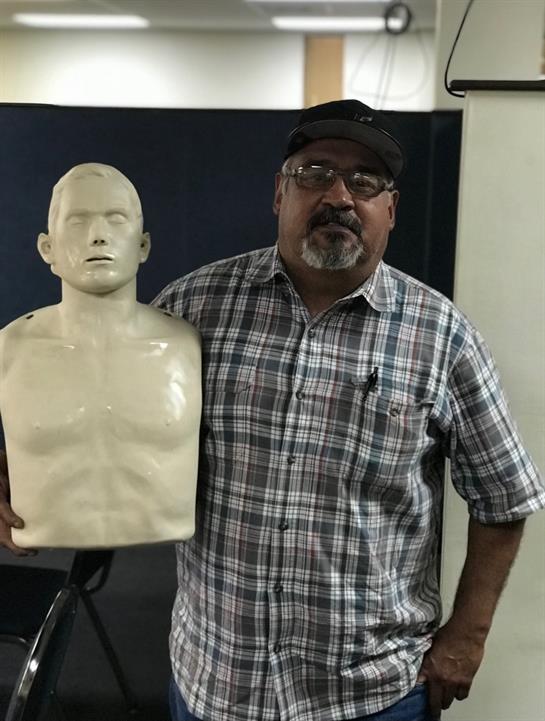 A man poses with a training mannequin during a safety demonstration at the facility.