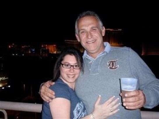 Joyful couple poses together under the night sky at a social event with lights in the background.