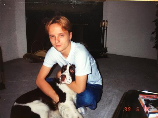 A young person relaxes on the carpet, hugging a friendly dog in a warm, inviting living room.