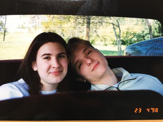 Two young people share a moment inside a car with nature visible outside the window.