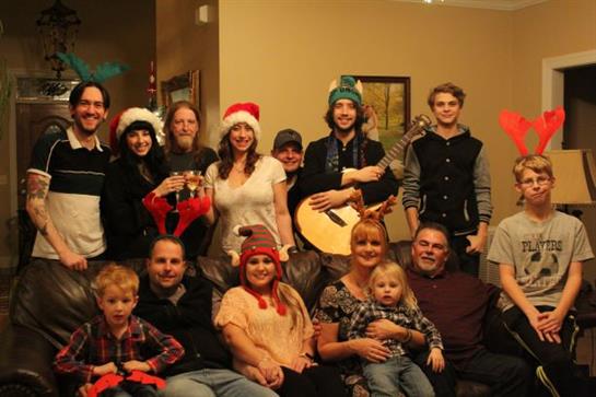 A cheerful group celebrates the holidays together in festive hats, sharing music.
