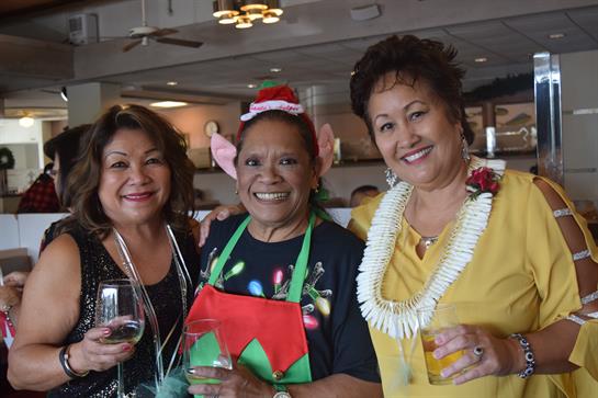 Three friends enjoy drinks while dressed in festive outfits at a vibrant restaurant gathering.