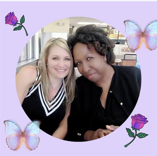 Two women enjoy a moment at a café, laughing and posing together amid decorative elements.