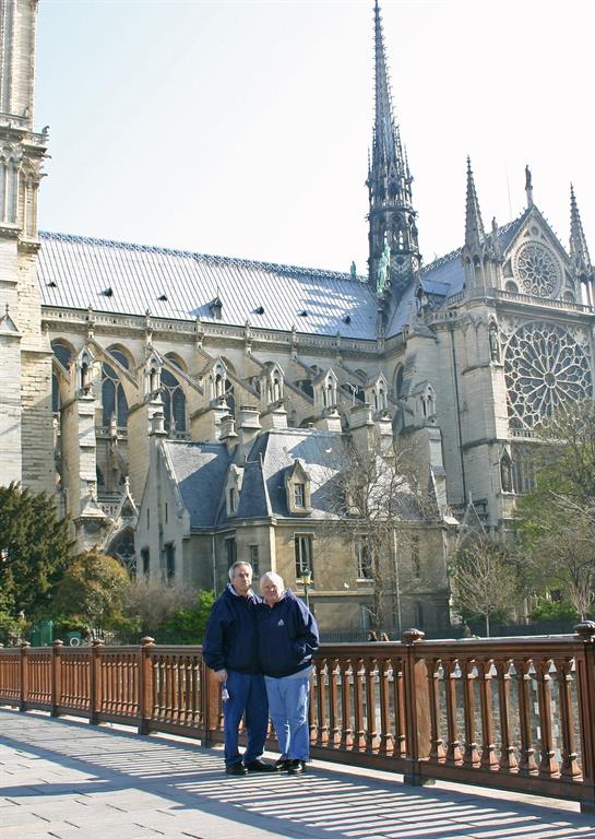 Couple stands smiling together near a grand cathedral, showcasing its beautiful architecture.