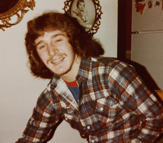 A young man with curly hair relishes a joyful moment in a cozy, vintage-decor home.