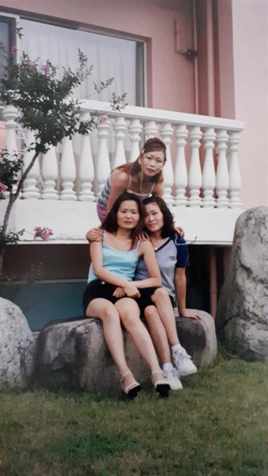 Three friends enjoy each other's company while sitting on rocks under a sunny sky.