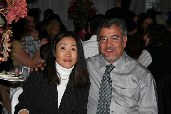 Two people pose for a photo while attending a lively social event in a banquet hall.