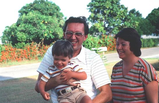 Happy family shares laughter and joy while playing together outside, surrounded by greenery.