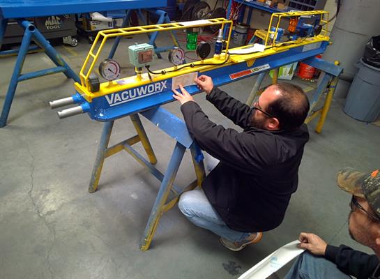 Technician kneels on the workshop floor, fine-tuning a machine for manufacturing tasks.