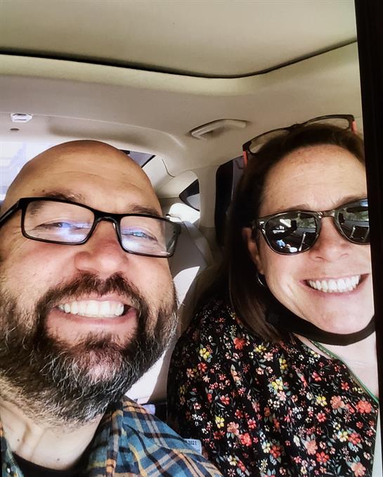Couple enjoys a cheerful moment, smiling and taking a selfie while traveling in a car.