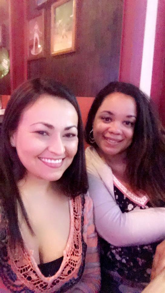 Two friends share smiles and laughter while relaxing in a warm, inviting cafe atmosphere.