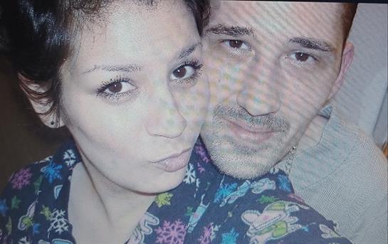 A couple enjoys each other's company, smiling playfully while taking a close-up selfie indoors.