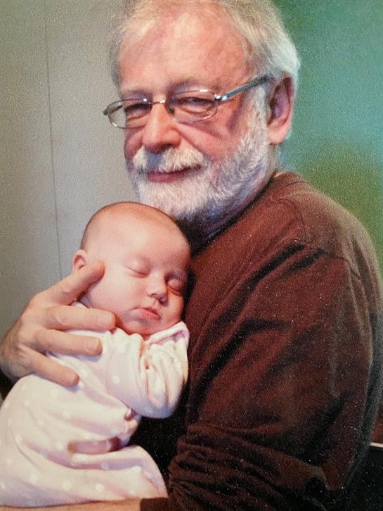 A loving grandfather cradles his peacefully sleeping grandchild in a warm, inviting environment.