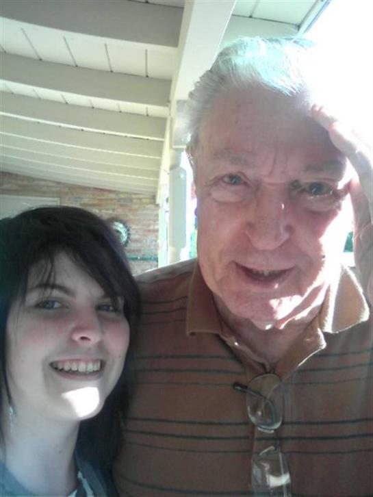 Two people happily smile together in a warm, outdoor setting.
